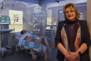 Victorine de Graaf-Peters bij een van de ‘immersive rooms’ van Windesheim. In een qua inrichting, beeld en geluid levensechte ruimte, van ziekenhuiskamer tot vliegtuigcabine, leren studenten adequaat te handelen wanneer een patiënt bijvoorbeeld een crisissituatie beleeft of een agressief persoon amok maakt. “Ziekenhuizen merken dat studenten er beter worden voorbereid op toekomstige werksituaties. Of studenten haken na één dag af omdat ze merken dat het werk niets voor hen is. In beide gevallen zijn onze immersive rooms heel effectief.” (Foto’s: Arjan Reef)